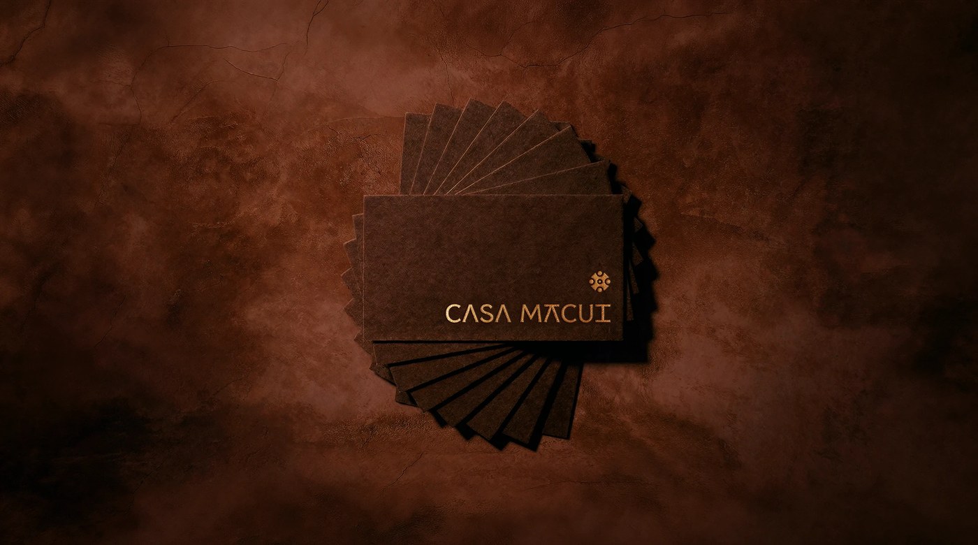 Casa Macui Mexican knife brand identity dark brown branded envelopes balanced on river rock against terracotta background
